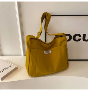 Detail of yellow canvas tote bag showing the adjustable shoulder strap and metal buckle