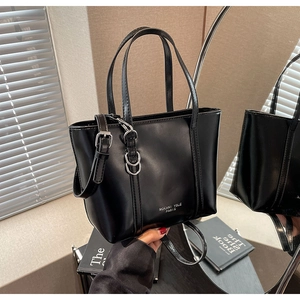 Detailed view of black leather tote bag with silver chain and brand logo engraving