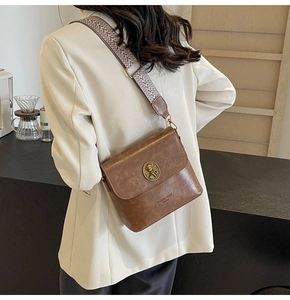 Détail d'un sac seau rétro marron avec large bandoulière jacquard et boucle dorée