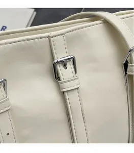 Gros plan du sac en cuir crème montrant la boucle argentée 3D et les coutures fines
