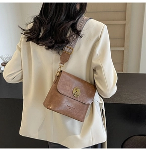 Détail du sac seau marron vintage avec boucle chat dorée et large bandoulière tissée