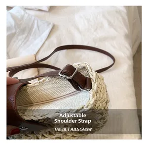 Detail showing adjustable brown leather strap and metal buckle on woven straw tote bag