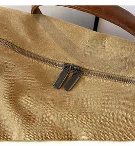 Close-up of durable gunmetal double zippers on a khaki canvas travel bag