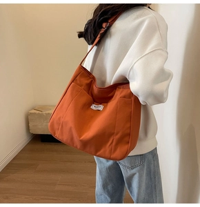 Detail of burnt orange canvas tote bag showing front pocket and woven label on model