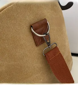 Detail of high-quality metallic D-rings and spring hooks on a khaki canvas travel bag