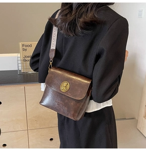 Détail du sac seau marron vintage avec boucle dorée et bandoulière en jacquard