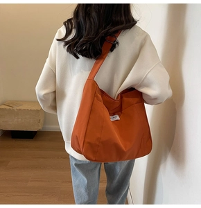 Detail showing the adjustable wide strap and texture of the orange canvas tote bag
