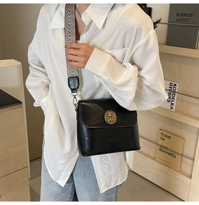 Détail du sac seau noir vintage avec emblème doré et large bandoulière tissée
