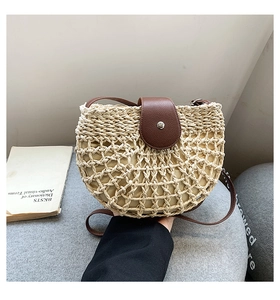 Detail of hollow-out straw texture and brown leather flap with metallic magnetic clasp