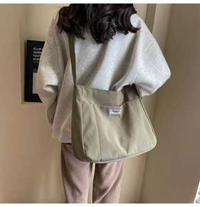 Close-up of khaki green canvas tote bag with fashion brand label and vertical stitching