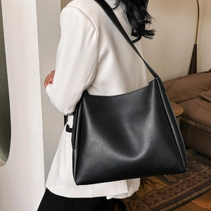 Minimalist black faux leather large bucket bag styled with a white blazer for women