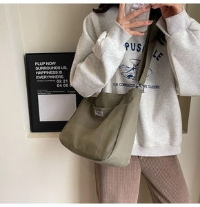 Close-up of khaki green canvas crossbody bag with pocket and woven brand label