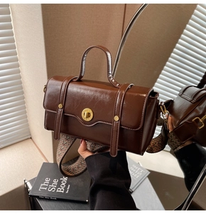 Detail of dark brown vintage handbag with golden lock and geometric wide strap in mirror reflection