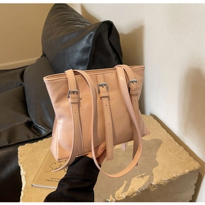 Détail du sac cabas rose avec boucles argentées posé sur une base en pierre texturée