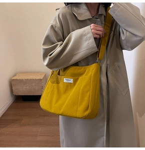 Detailed view of yellow canvas tote bag featuring BUDBAO FASHION woven label and wide strap