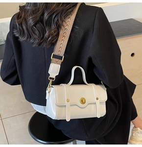 Detail of cream crossbody bag with wide geometric pattern strap on a model