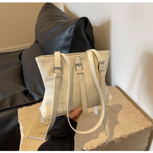 Détail d'un cabas blanc cassé avec boucles en métal argenté et fines lanières de cuir
