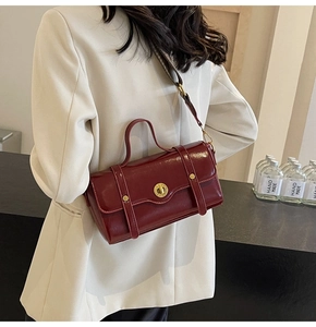 Detail of burgundy patent leather satchel with golden twist lock and retro buckle design