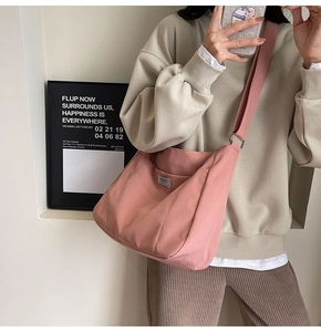 Detailed view of pink canvas tote bag showing wide shoulder strap and brand label