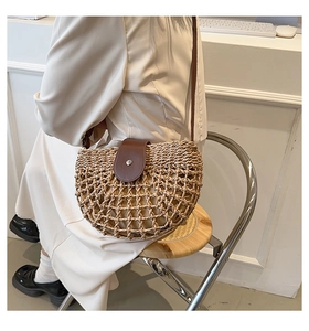 Detail showing the woven hollow straw texture and brown leather flap with metal buckle