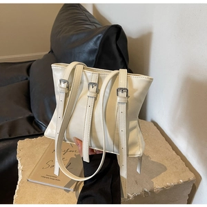 Détail du sac cabas crème en cuir avec trois boucles argentées et texture raffinée