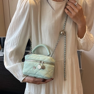 Minztürkise Mini-Eimertasche mit Rautensteppung, Kette und Griff an einem Modell