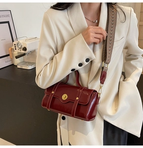 Detail of burgundy crossbody bag with gold buckle and jacquard woven shoulder strap