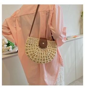 Detail of a french style straw woven tote bag worn with a pink shirt and white pleated skirt