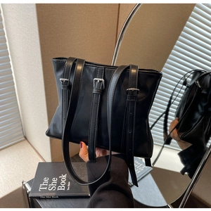 Détail d'un sac cabas noir avec sangles décoratives et boucles argentées en décor intérieur