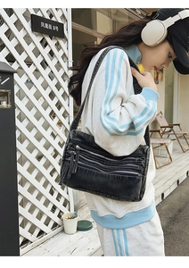 Detail of washed denim shoulder bag featuring three layered zippers and utility style