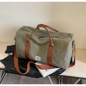 Detail of army green canvas travel bag with brown leather handles and adjustable strap