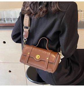 Brown retro crossbody bag with wide geometric woven strap and metal rotary buckle detail