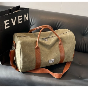 Olive canvas duffle bag with brown leather handles on a leather sofa for short travel