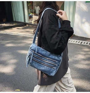 Detail of vintage blue denim tote bag featuring multi-layer metal zippers and street style