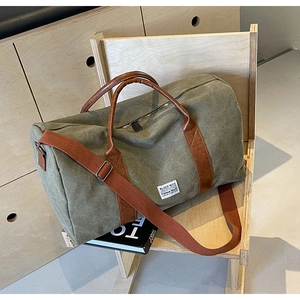 Detail of army green canvas travel bag with leather handles on a wooden chair