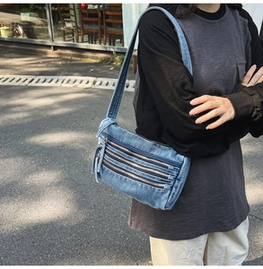 Detail of dark blue denim tote bag featuring four layered metal zippers and workwear style