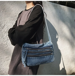 Detail view of denim tote bag with triple zipper pockets and stylish long fringe tassels