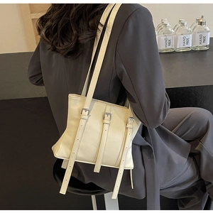 Détail d'un sac cabas en cuir blanc cassé avec boucles argentées porté à l'épaule