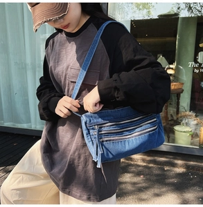 Blue denim crossbody tote bag with three front zippers shown on a model in a casual setting