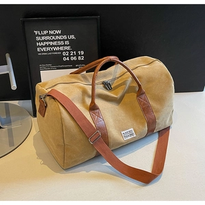 Detail of khaki canvas travel bag with brown leather trim and wide shoulder strap