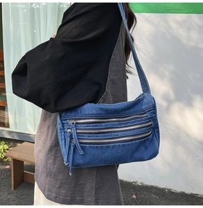 Close-up of vintage blue denim tote bag featuring triple front zipper pockets for daily use