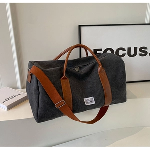 Detail of grey canvas travel bag with leather handles and a minimalist white label