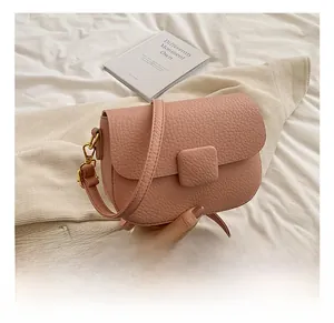 Detailed close-up of pink litchi grain texture and golden hardware on crossbody bag