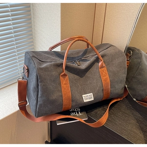 Dark grey canvas travel bag with brown leather straps and adjustable shoulder strap