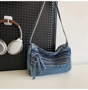 Detail view of washed denim bag featuring retro metal zippers and thick fabric texture