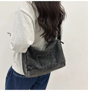 Détail du sac cabas en denim noir avec surpiqûres contrastées et une poche extérieure