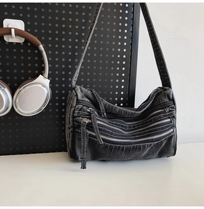 Detail of black denim tote bag featuring three silver zippers and washed vintage finish