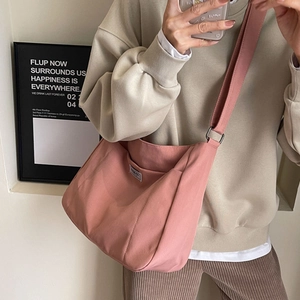 Pink canvas hobo crossbody tote bag with wide strap and minimalist woven label