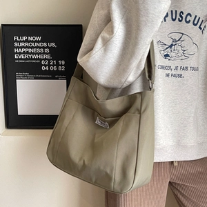 Olive green canvas tote bag with front pocket and wide strap for crossbody commuting