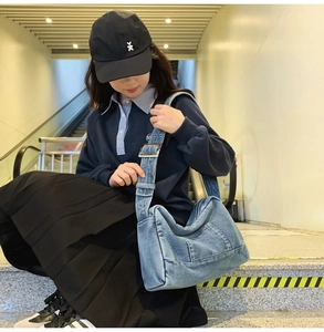 Gros plan du sac cabas en denim bleu clair avec large bandoulière et boucle en métal argent